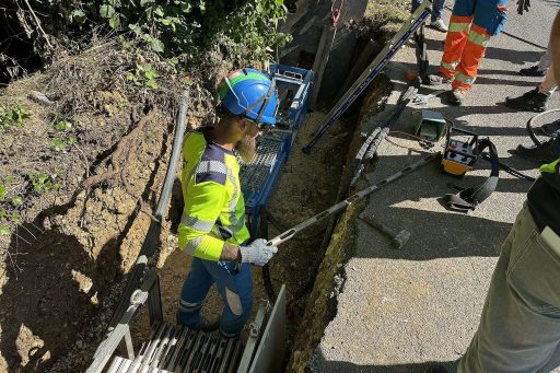 Un homme vêtu d'un gilet jaune et d'un casque bleu est dans une tranchée