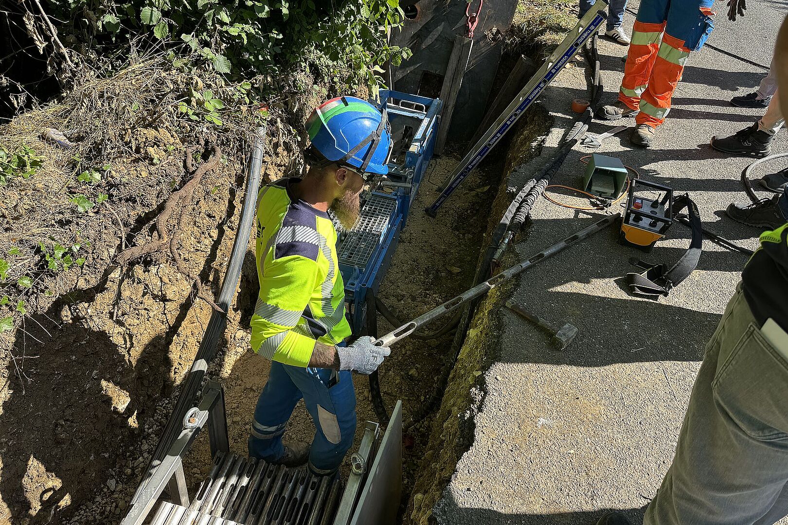 Un homme vêtu d'un gilet jaune et d'un casque bleu est dans une tranchée