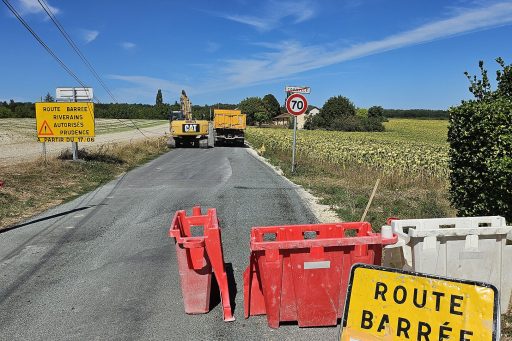Des tractopelles refont une route. Cette route se situe après Cornille, un panneau l'indique. Il y a aussi des plots et des cônes de chantier.