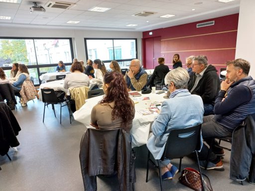 Des personnes sont réunies autour de petites tables. Elles échangent entre elles.