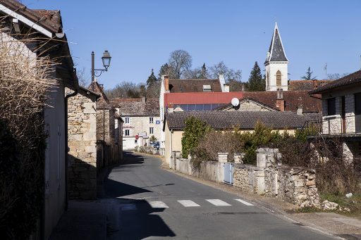 Une rue traverse le village. De chaque côté, des murs, des bâtiments en pierre.