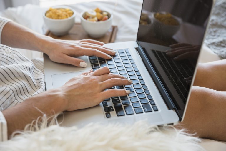 Une femme pianote sur un clavier d'ordinateur. Il y a à côté de l'écran des bols avec des cacahuètes.