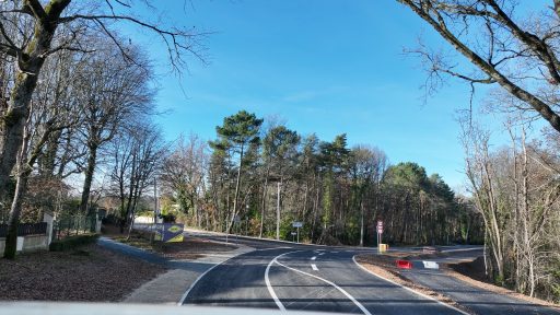 Sous un ciel bleu, la route principale de couleur grise Marival offre plusieurs tracés blancs au sol