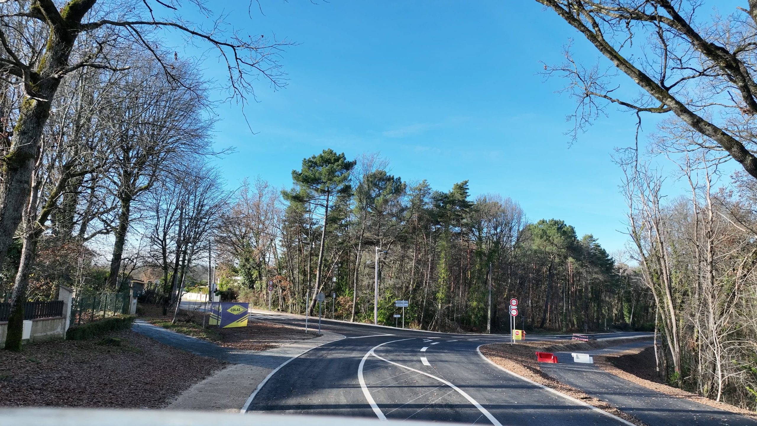 Sous un ciel bleu, la route principale de couleur grise Marival offre plusieurs tracés blancs au sol