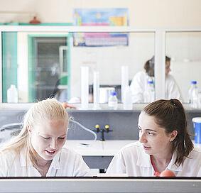 Deux jeunes filles habillées en blouse blanche étudient dans un laboratoire