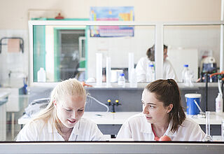 Deux jeunes filles habillées en blouse blanche étudient dans un laboratoire