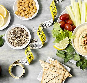 coupelle avec houmous vue de dessus avec assortiment de légumes (carotte, céleri) et ruban pour mesurer la taille 