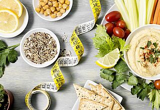 coupelle avec houmous vue de dessus avec assortiment de légumes (carotte, céleri) et ruban pour mesurer la taille 